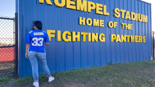 Women in blue jersey standing at football field